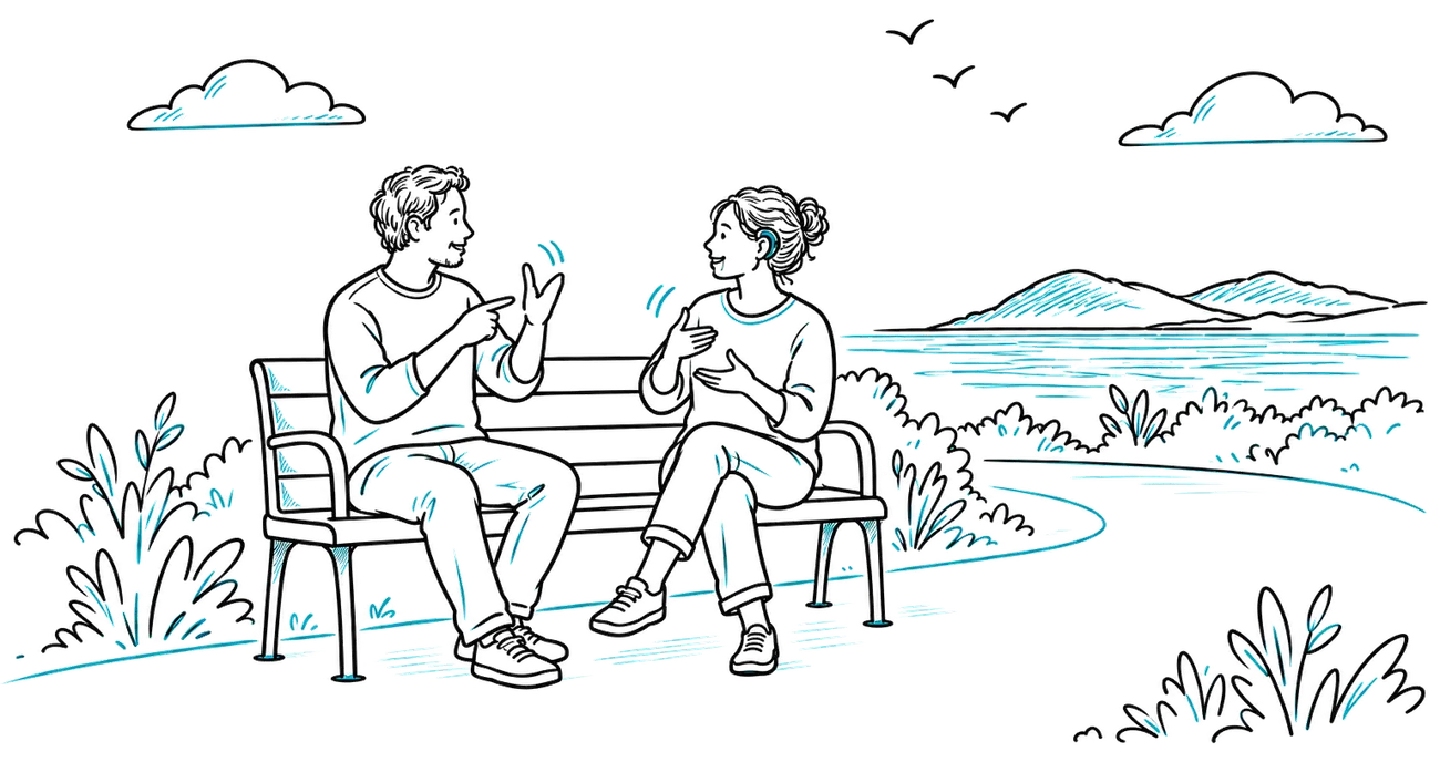 Two people on a bench by the sea, chatting in sign language